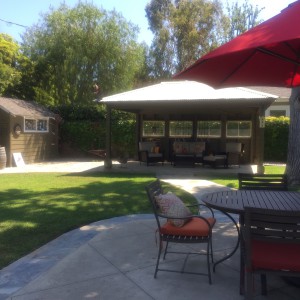 in the foreground, peaceful patio seating, right by the built-in barbecue. at the other side of the yard is a shady cabana and a valuable storage shed.